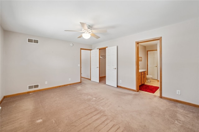 unfurnished bedroom with a closet, light colored carpet, ensuite bathroom, and ceiling fan