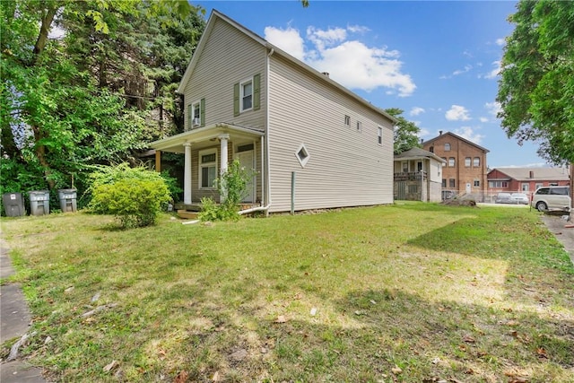 view of side of property featuring a yard and covered porch