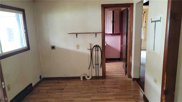 hall with a healthy amount of sunlight and hardwood / wood-style floors