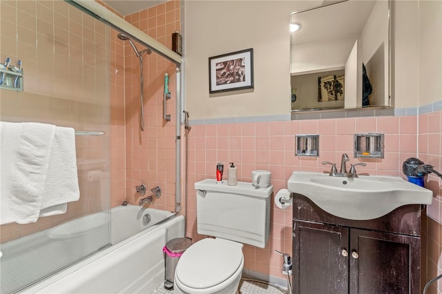 112 Washington Pl Unit 7E, Downtown Pgh, PA 15219 - bathroom with tile walls, combined bath / shower with glass door, vanity, toilet, and wainscoting