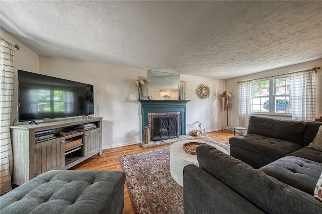 living room with light wood-type flooring, a textured ceiling, a fireplace, and lofted ceiling