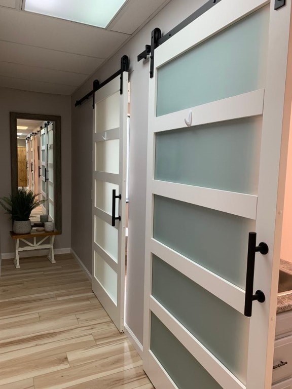 corridor featuring light hardwood / wood-style flooring and a barn door