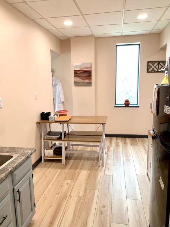 kitchen featuring a paneled ceiling, light wood-type flooring, and gray cabinetry