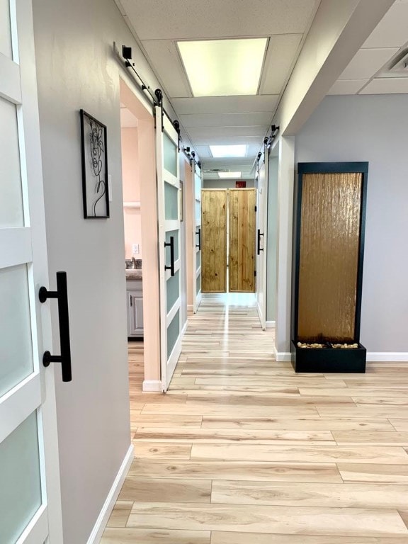 hallway featuring light hardwood / wood-style flooring, sink, and a barn door