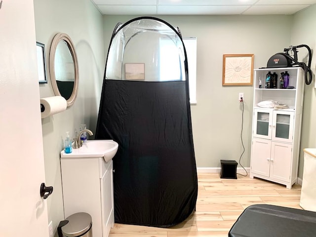 bathroom with vanity, wood-type flooring, and a drop ceiling