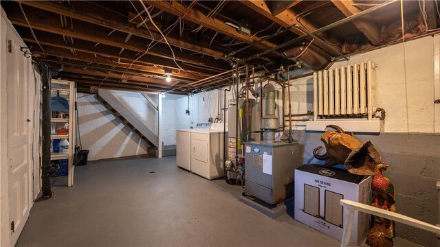 basement featuring washing machine and clothes dryer, heating unit, and gas water heater