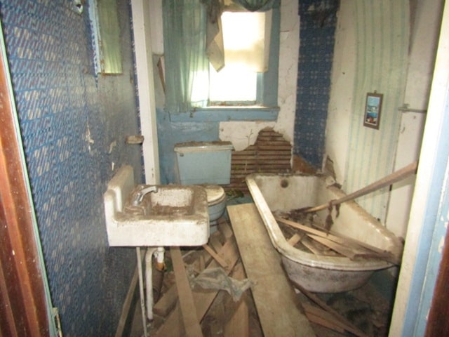 bathroom featuring sink, a bath, and toilet