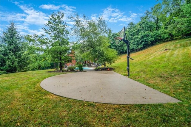 view of home's community featuring basketball hoop and a lawn