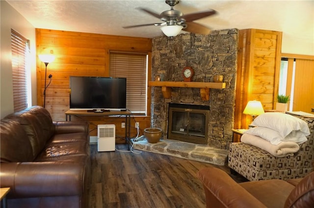 living area with wooden walls, ceiling fan, a fireplace, and wood finished floors