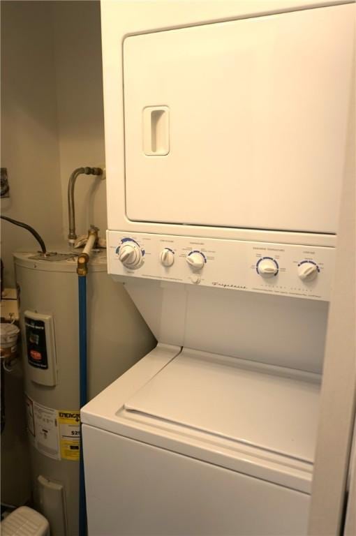 laundry area with water heater, stacked washer and dryer, and laundry area