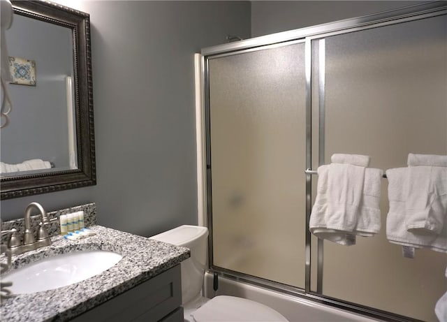 full bathroom with toilet, combined bath / shower with glass door, and vanity