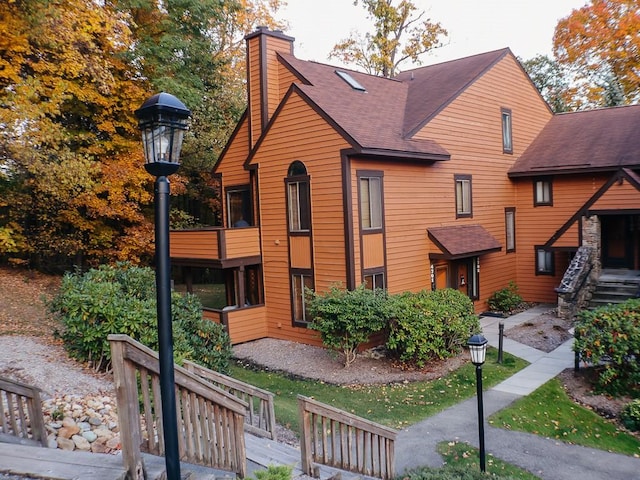 view of front of house with roof with shingles and a chimney