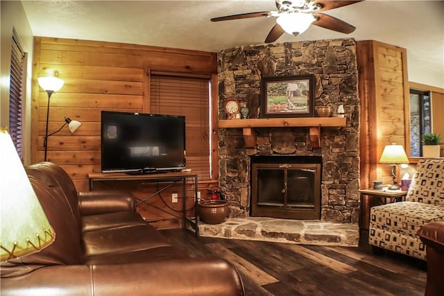 living room featuring ceiling fan, wood walls, a stone fireplace, and wood finished floors