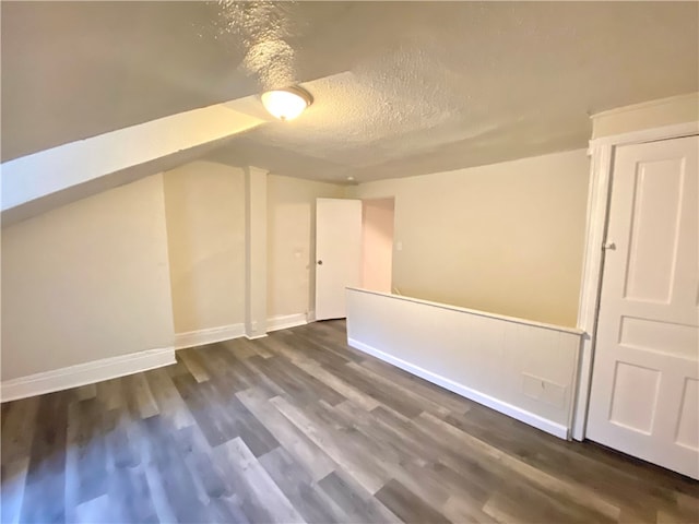 additional living space with dark wood-type flooring and a textured ceiling