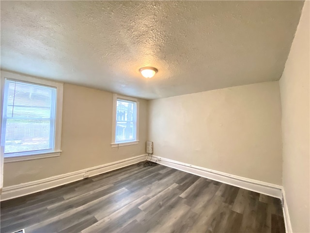 spare room featuring a textured ceiling and dark hardwood / wood-style floors