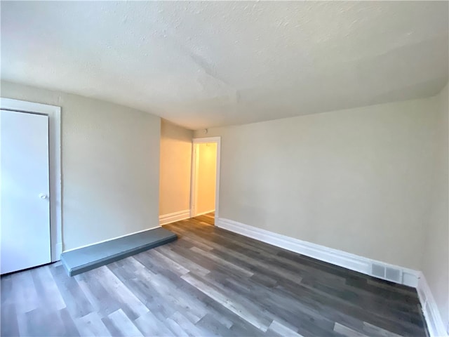 spare room with a textured ceiling and wood-type flooring