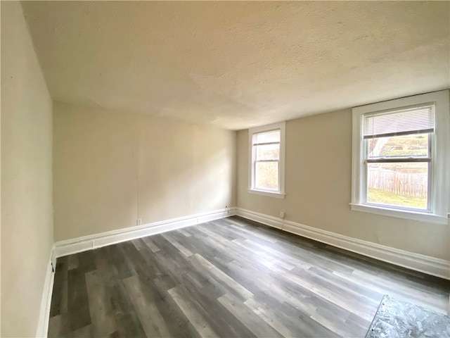 spare room with a textured ceiling, dark hardwood / wood-style flooring, and plenty of natural light