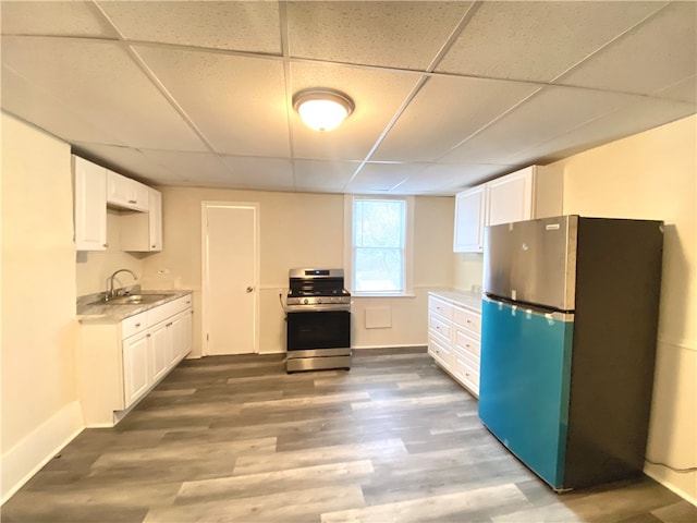 kitchen featuring white cabinets, hardwood / wood-style flooring, a paneled ceiling, and stainless steel appliances