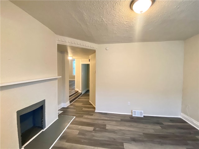 empty room with dark hardwood / wood-style flooring and a textured ceiling