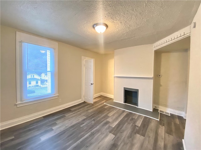 unfurnished living room featuring a textured ceiling and dark hardwood / wood-style flooring