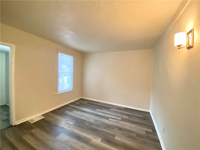 empty room featuring dark hardwood / wood-style floors and a textured ceiling