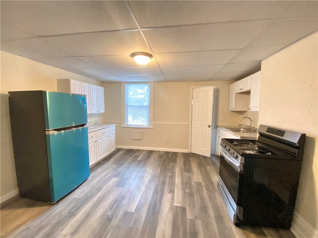 kitchen with range, wood-type flooring, a drop ceiling, and black refrigerator