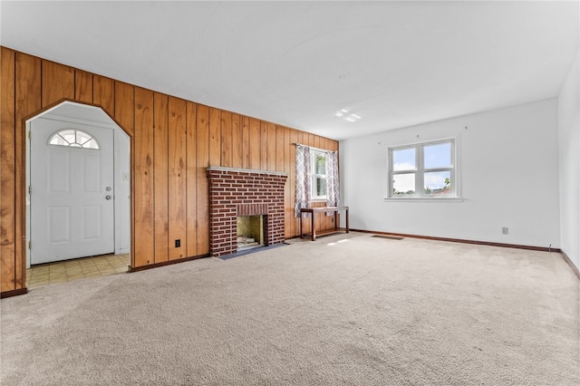 unfurnished living room featuring wood walls, a fireplace, and light carpet