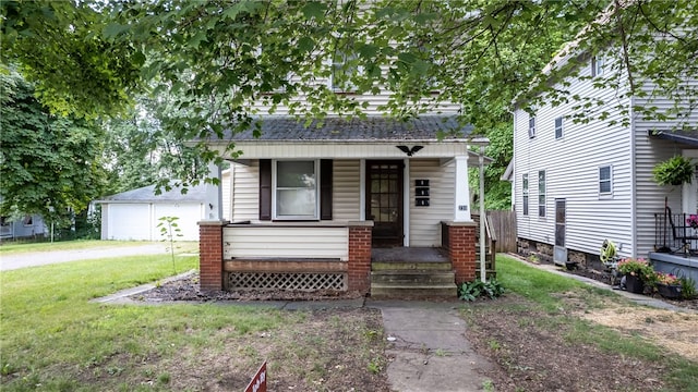 view of front of property featuring a garage, a front lawn, an outdoor structure, and covered porch