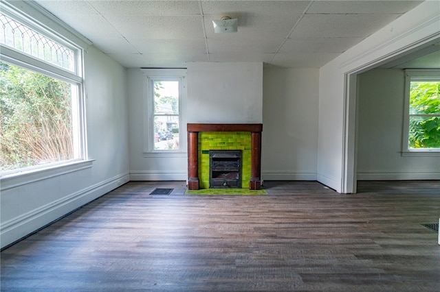 unfurnished living room featuring wood-type flooring, baseboard heating, and a paneled ceiling