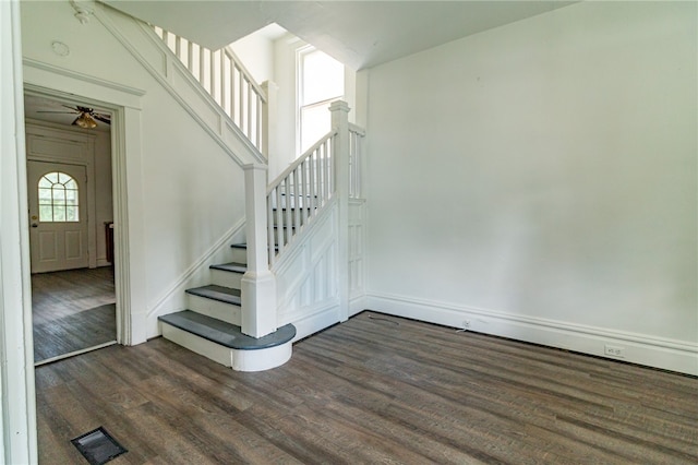 stairs with dark hardwood / wood-style floors, ceiling fan, and a towering ceiling