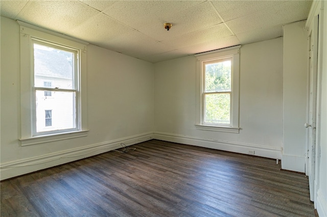 empty room with a paneled ceiling and dark wood-type flooring