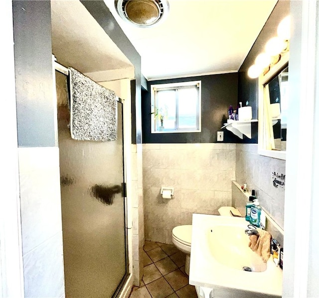 bathroom with tile walls, toilet, a shower with door, and tile patterned floors