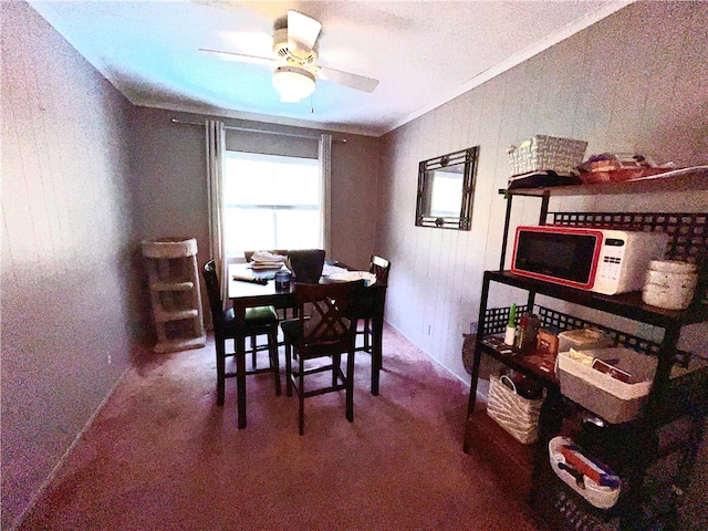 carpeted dining space featuring ornamental molding and ceiling fan