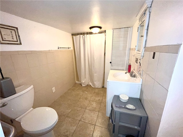 bathroom with tile walls, vanity, toilet, and tile patterned floors