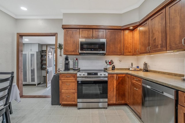 kitchen with ornamental molding, light tile patterned flooring, backsplash, and stainless steel appliances