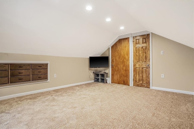 additional living space featuring light colored carpet and vaulted ceiling