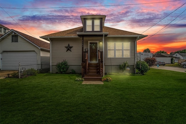 back house at dusk with a garage and a yard