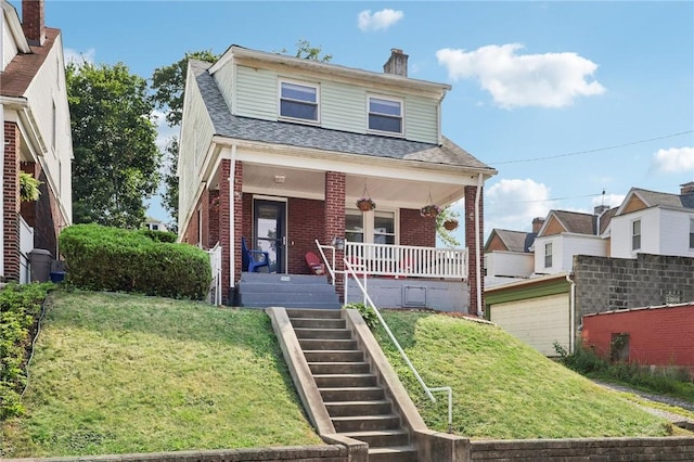 view of front of property featuring a porch, a garage, and a front lawn