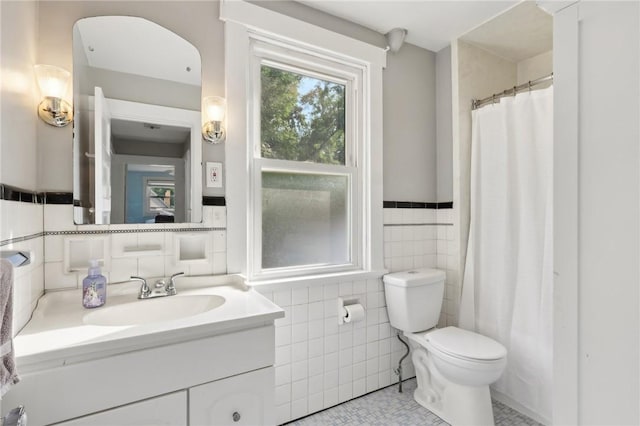 bathroom featuring vanity, toilet, tile walls, and tile patterned flooring