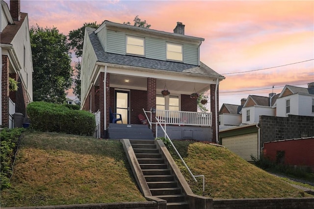 bungalow-style house featuring covered porch and a lawn