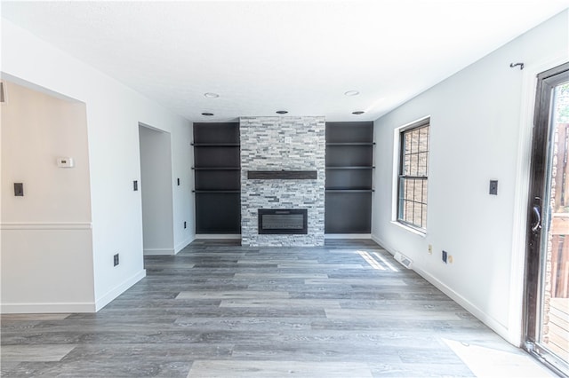 unfurnished living room featuring built in features, a fireplace, and hardwood / wood-style flooring