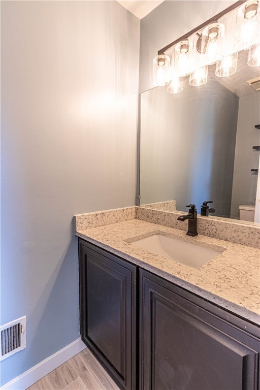 bathroom featuring vanity, wood-type flooring, and toilet