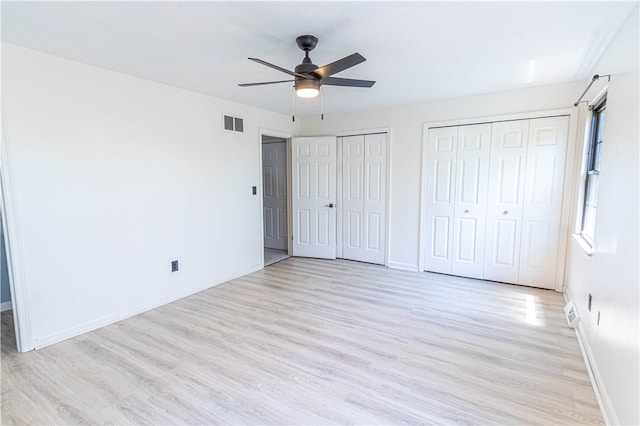 unfurnished bedroom featuring light hardwood / wood-style floors, two closets, and ceiling fan