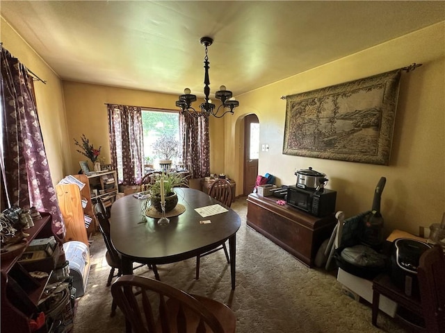 carpeted dining space featuring a chandelier and arched walkways