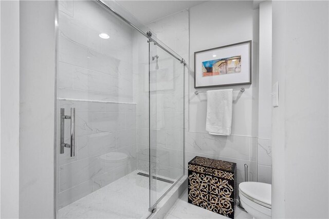 bathroom with tile patterned floors, a shower with door, tile walls, and toilet