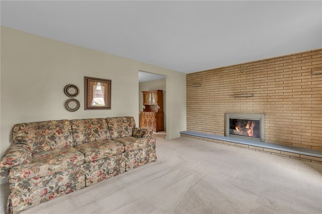 unfurnished living room featuring brick wall, a fireplace, and carpet