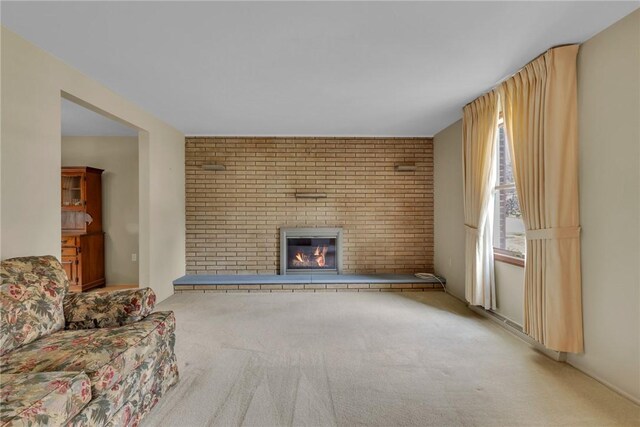 unfurnished living room with a fireplace, brick wall, and carpet floors