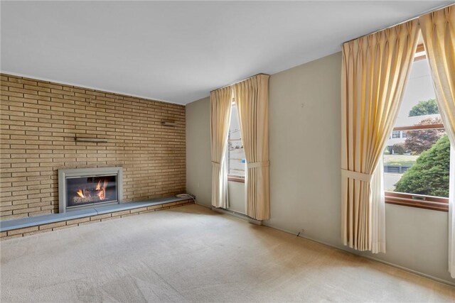 unfurnished living room featuring light colored carpet, a brick fireplace, and brick wall