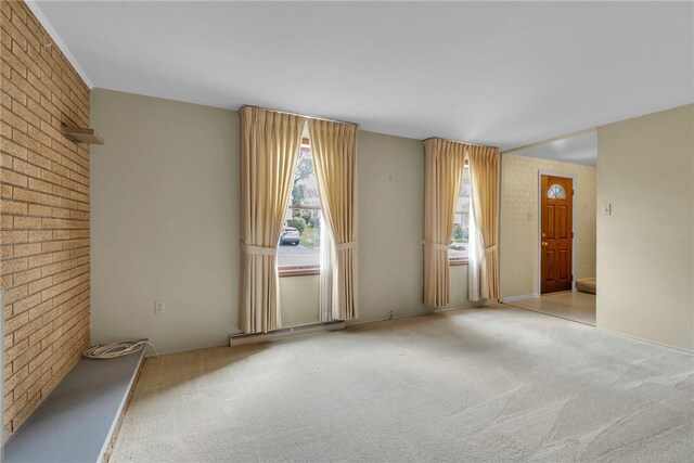 carpeted empty room with brick wall