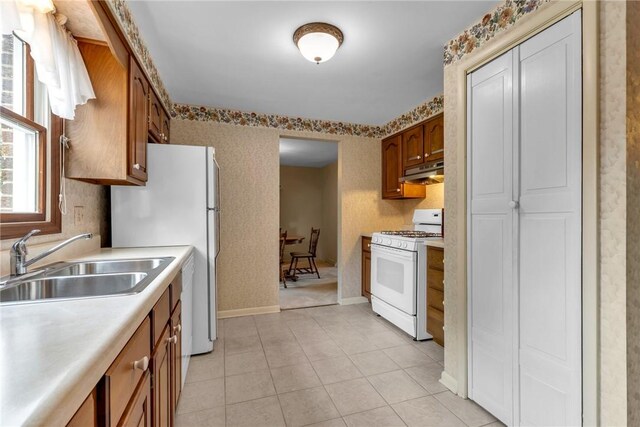 kitchen with light tile patterned floors, white gas range oven, and sink